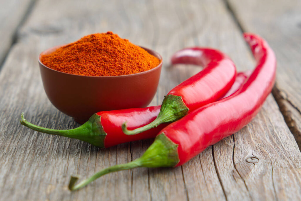 Cayenne peppers and powder on a wooden table, pungent in the 6 tastes of Ayurveda