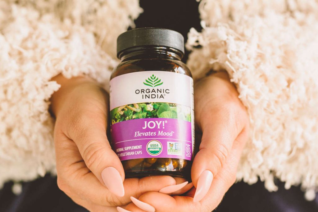 Woman holding joy supplement with adaptogens and nootropics for stress relif and productivity.