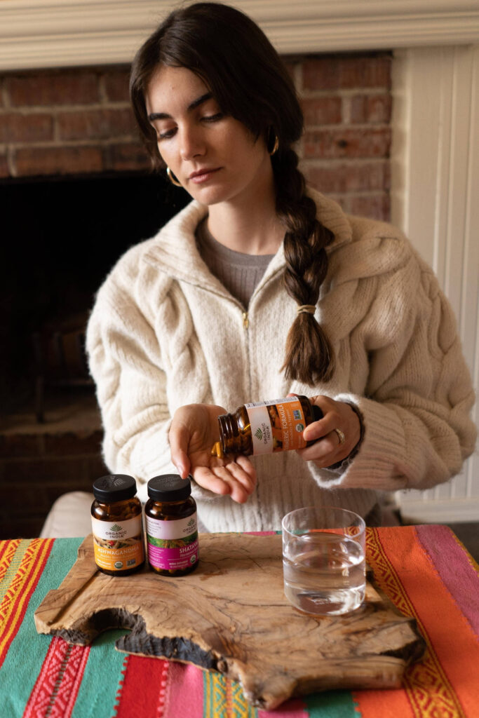 Woman taking herbal supplements including ashwagandha for hair. 