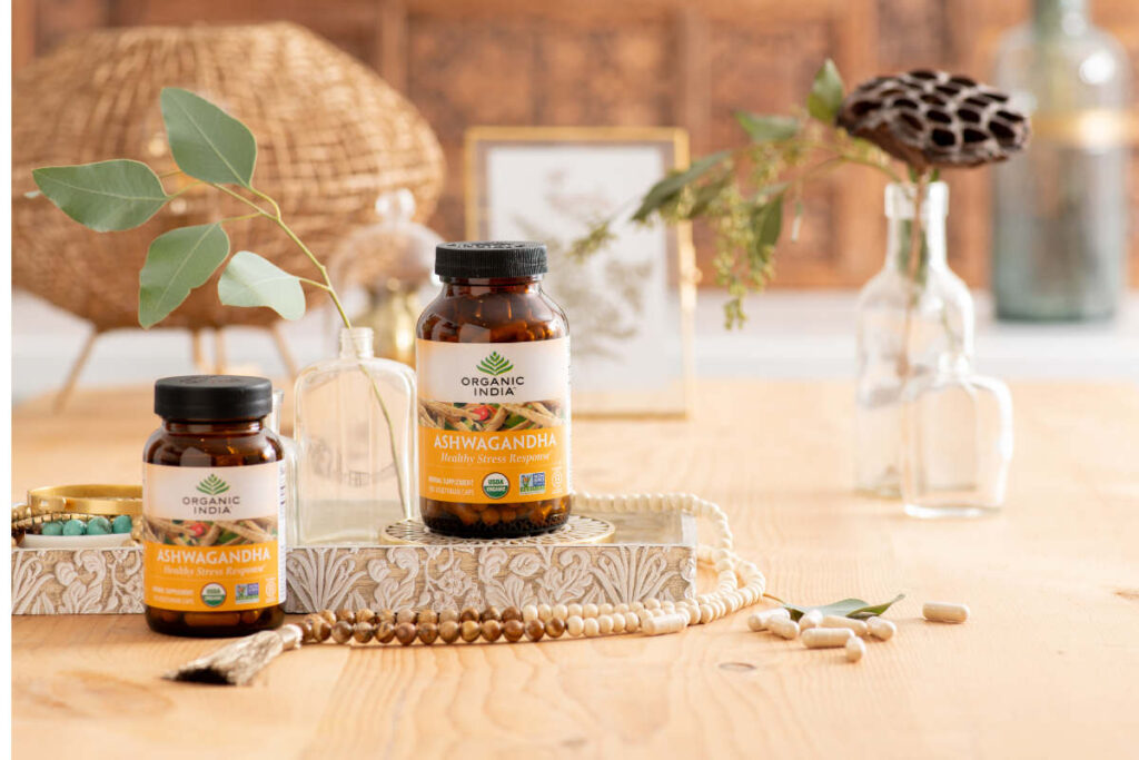 Ashwagandha on wooden table with mala and small clear flower pots.
