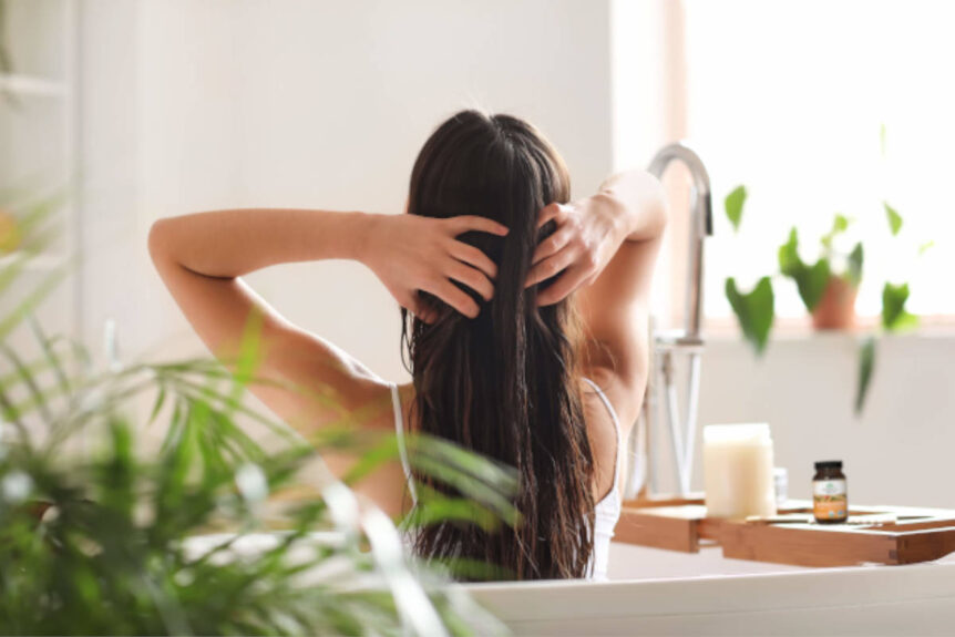 Woman surrounding by plants in bathroom applying a mask made from ashwagandha for hair health.