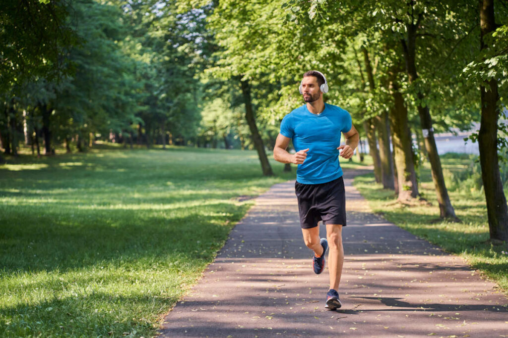Ashwagandha for men running through park with headphones in tshirt and shorts.