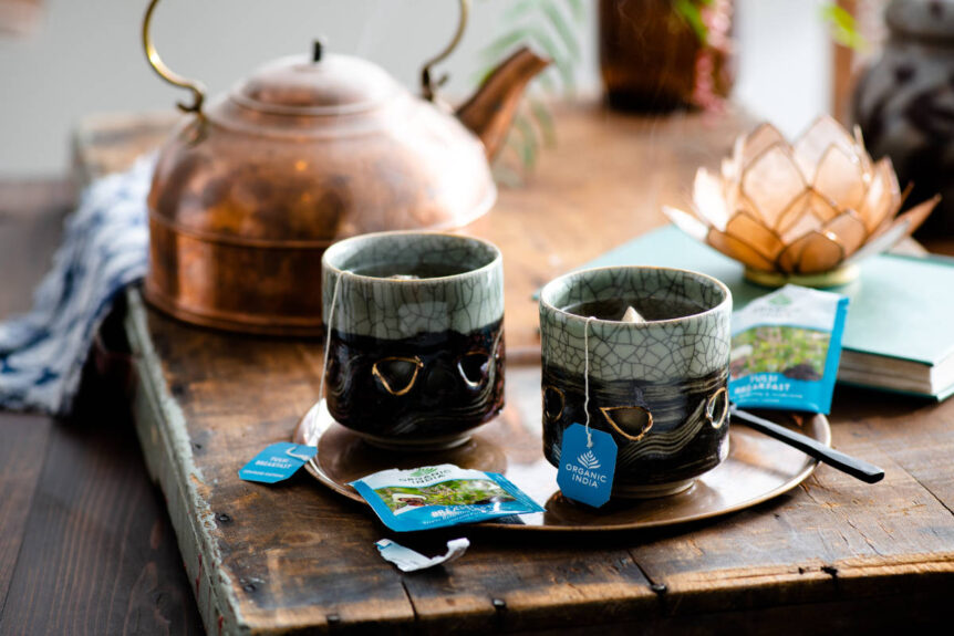 Tea made with bacopa benefits for brain on wood table with copper tea kettle.