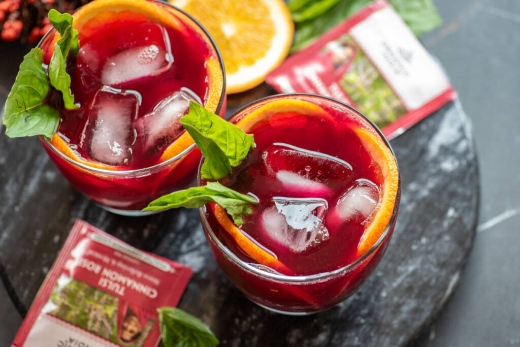 Beet Mocktail in clear glass with ice cubes and orange garnish.