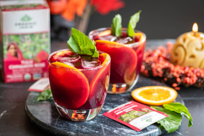 Beet Mocktail in clear glass with ice cubes and orange garnish.