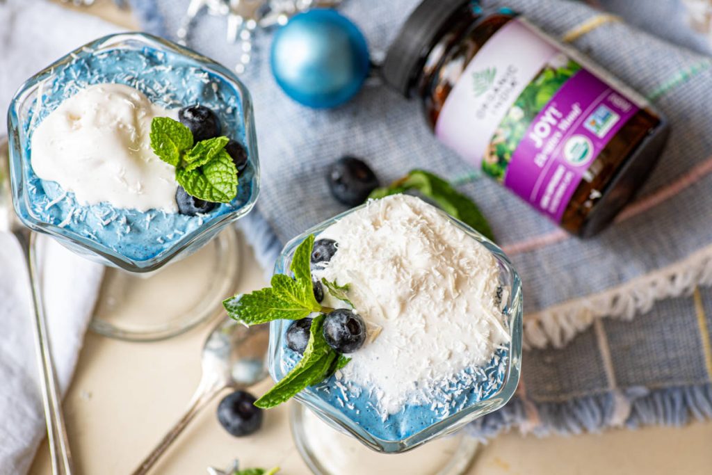 Blue majik mousse in a dessert glass with blueberry and mint garnish.