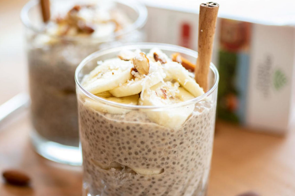 Small clear dessert glass full of chia chai pudding garnished with banana and cinnamon. 