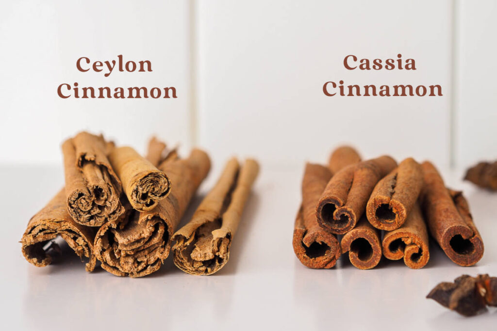 cassia vs ceylon cinnamon whole bark side-by-side comparison on white marble table with subway tile backsplash.