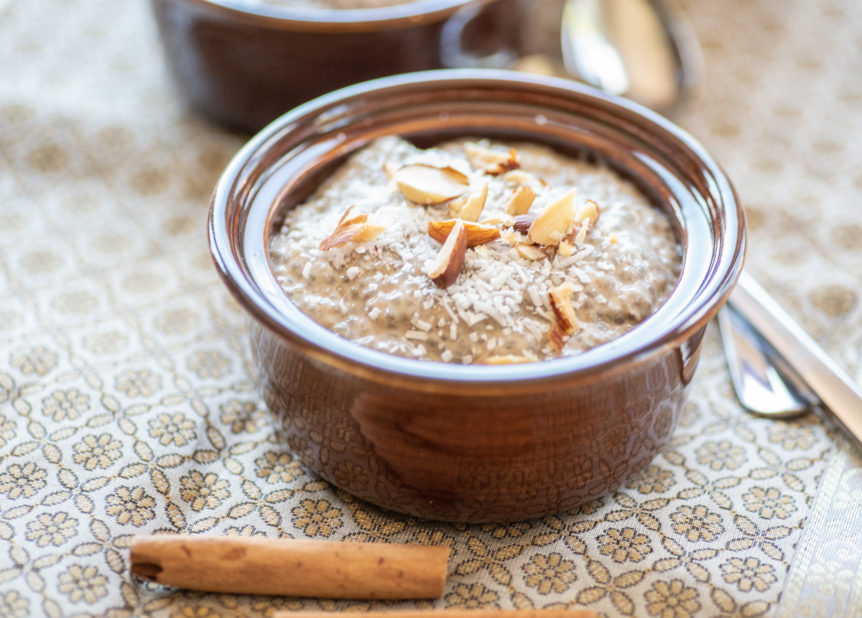 A dessert dish of chai chia pudding on a tablecloth with cinnamon.