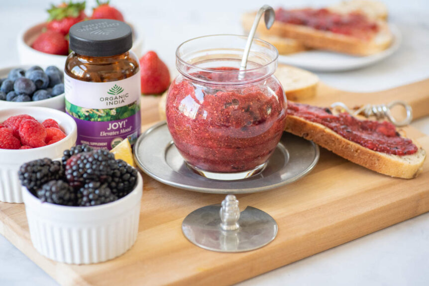 chia berry joy jam in glass container on cutting board with fresh fruit
