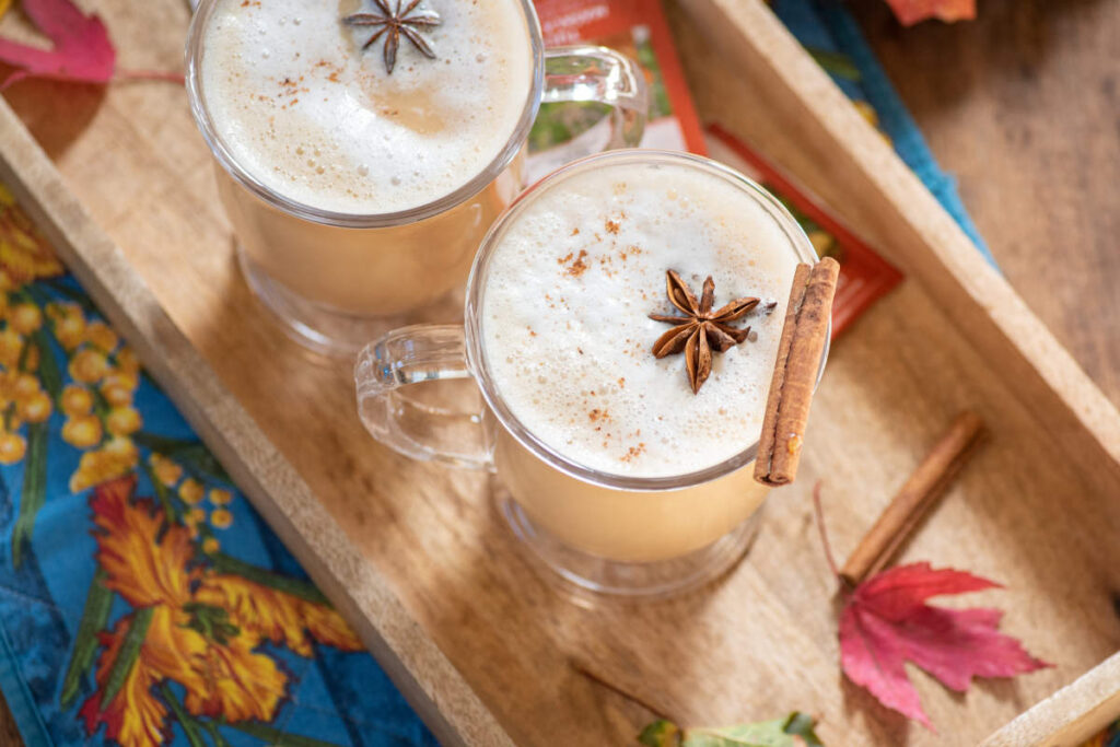 Classic Chai Tea latte with Tulsi in a clear mug with steamed milk and clove and cinnamon garnish.
