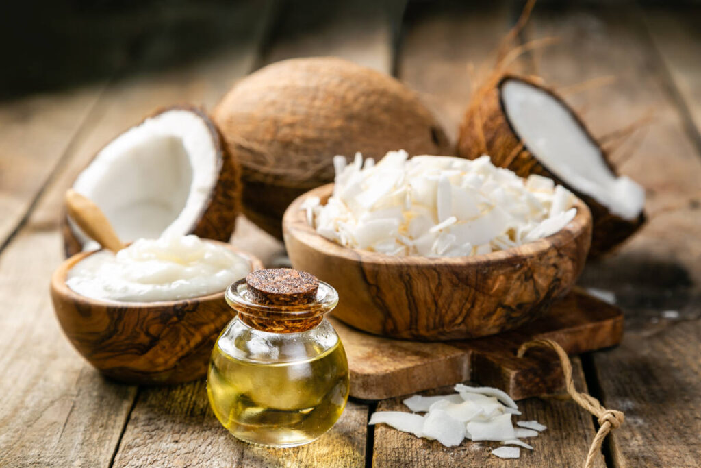 Whole coconut, flakes and oil for coconut oil pulling on wooden table.