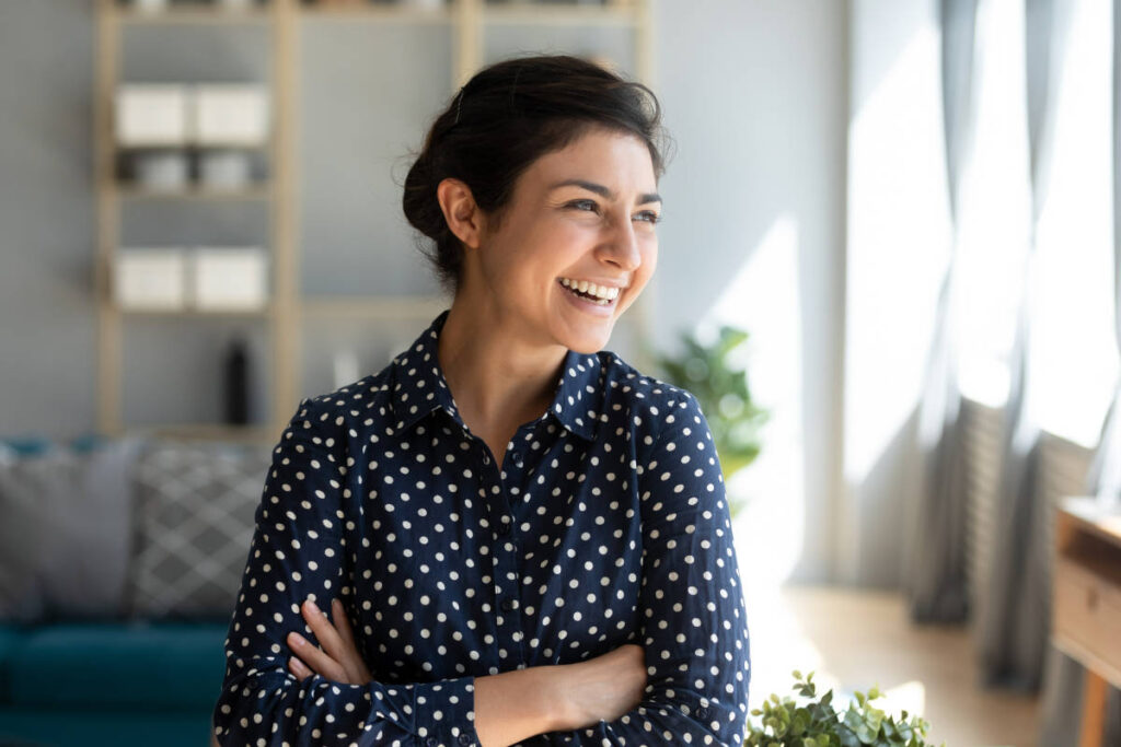 Woman smiling with white healthy teeth from coconut oil pulling in her sunny living room