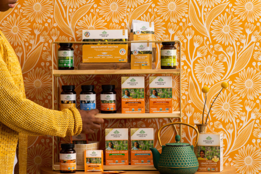 Woman in yellow sweater with wooden shelf full of expectorant herb teas and supplements