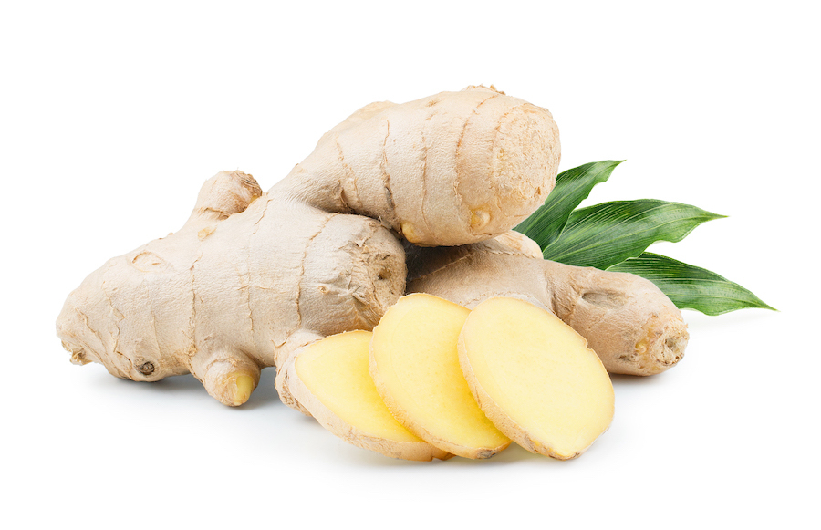 Ginger root whole and sliced with green leaves. 