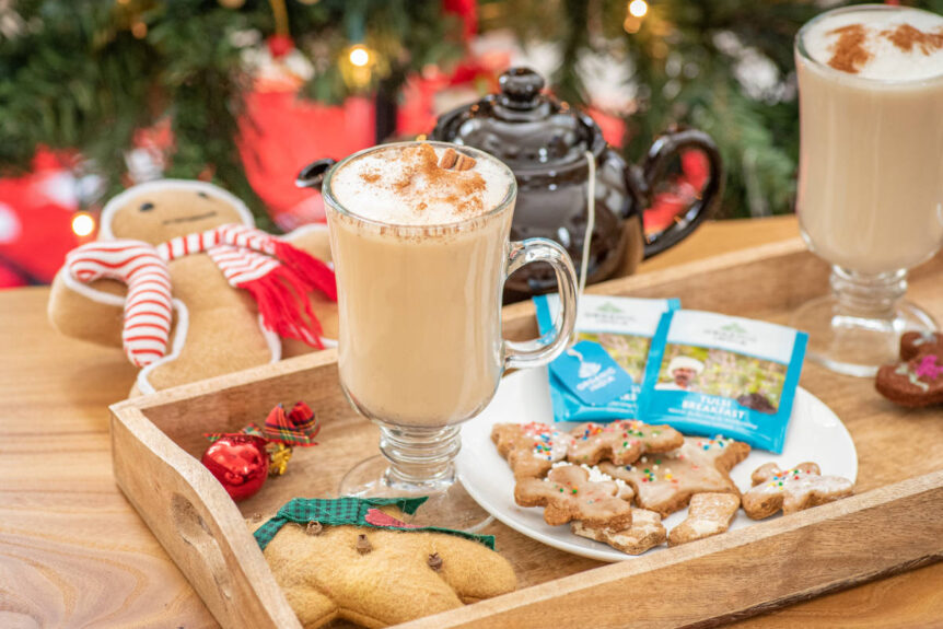 Gingerbread tea latte on wooden platter with gingerbread cookies and organic india tulsi breakfast tea.