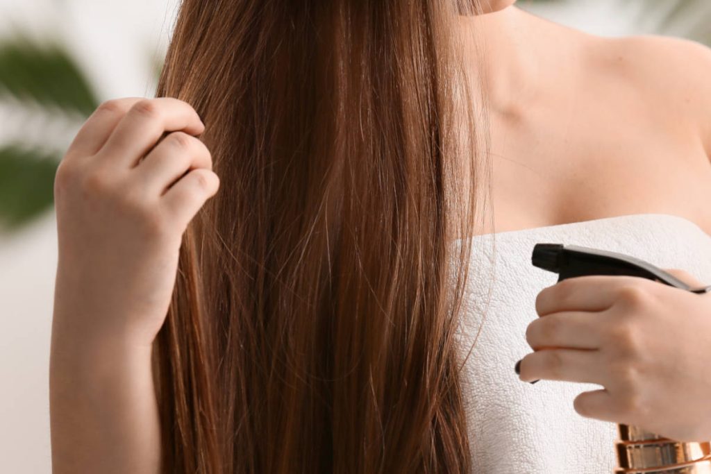 Women spraying long brown hair for haircare.