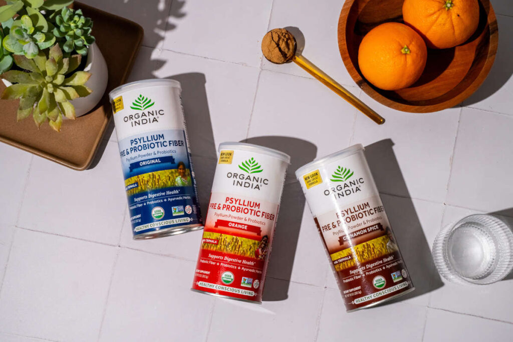 Psyllium Pre & Probiotic fiber canisters on kitchen table with succulent and orange for a happy, healthy gut.