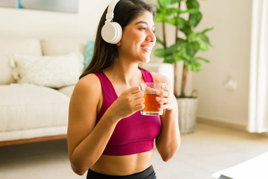 Woman doing yoga and listening to music while sipping tea featuring herbs for circulation.