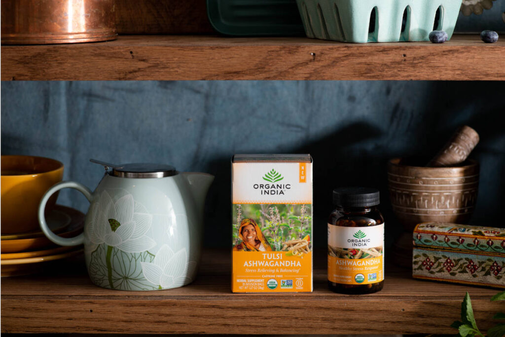 Ashwagandha supplement and tea for hormonal health on a wooden shelf with tea kettle and mortar and pestle. 