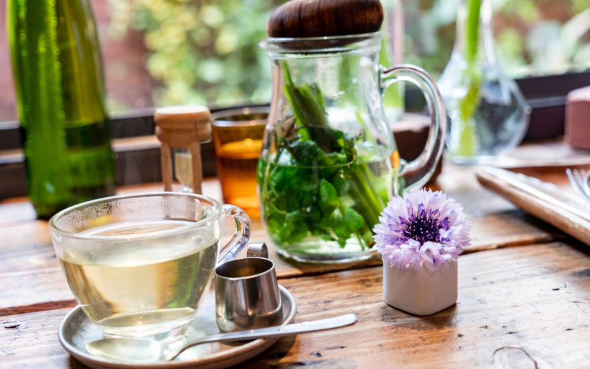 Herbs for stress relief and mood in a clear teacup with leaves infusing.