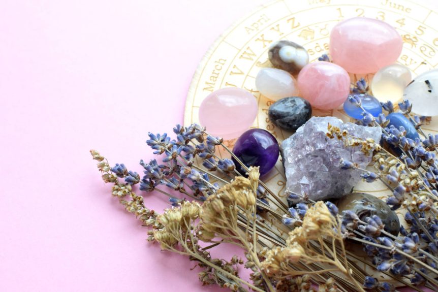 Herbs for the zodiac with crystals and star chart on a soft pick table.