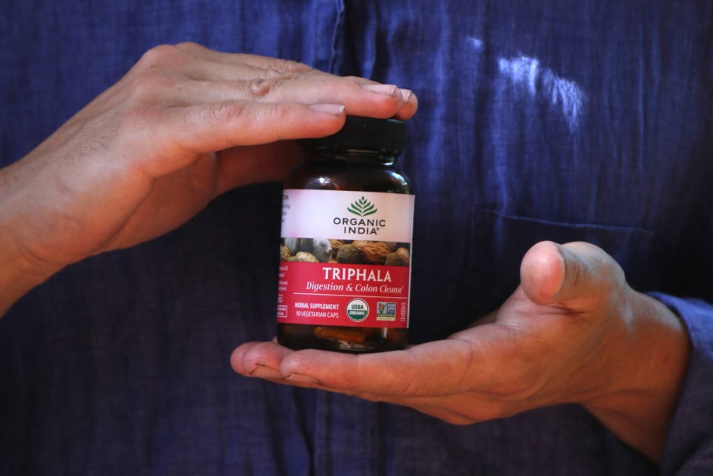 Man in blue button down holding Triphala.