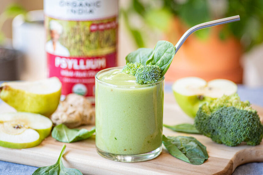 Green high fiber smoothie in a glass on a wood cutting board.