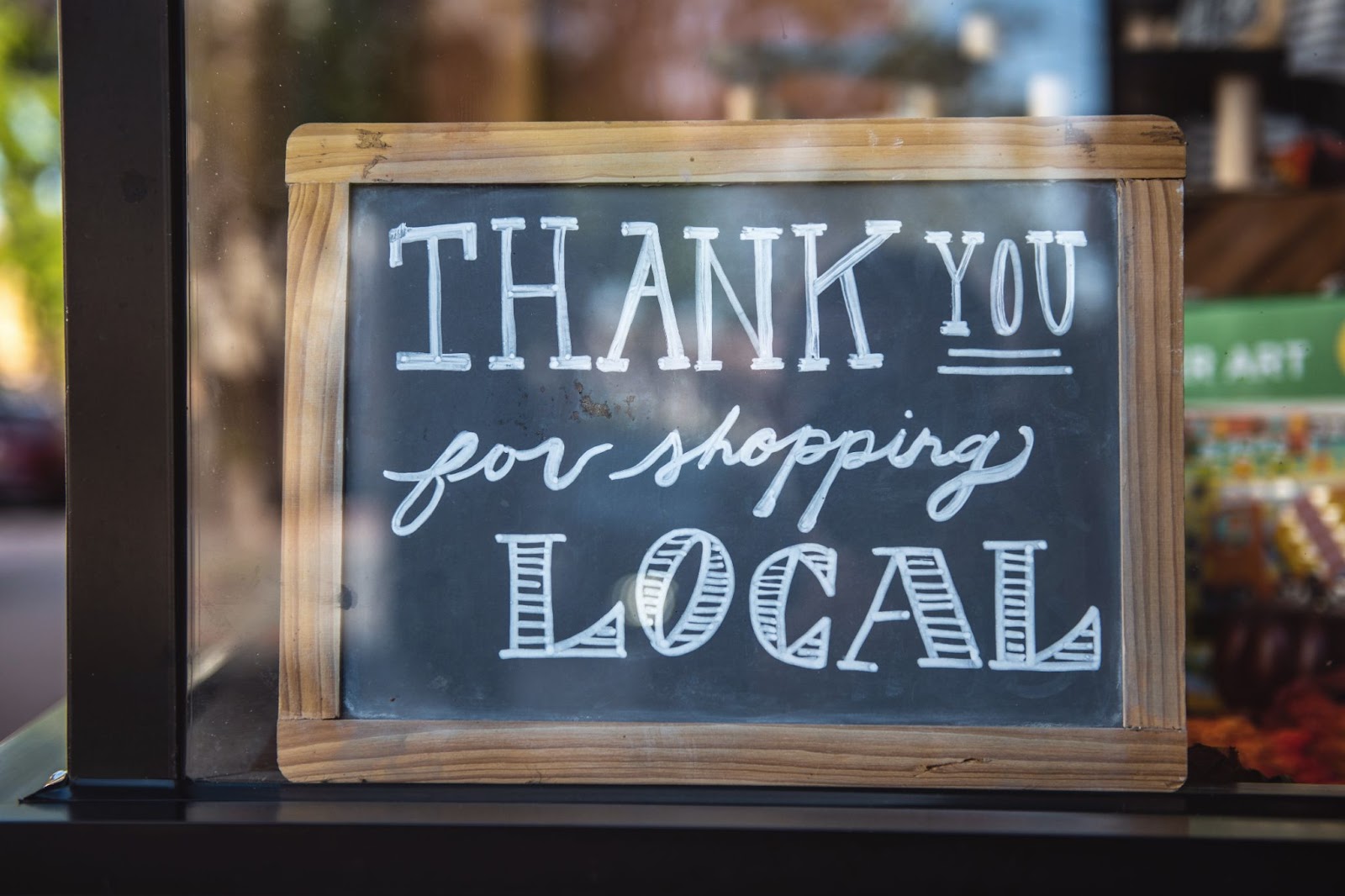 Black board in a wooden frame that says "thank you for shopping local" for conscious holiday shopping. 