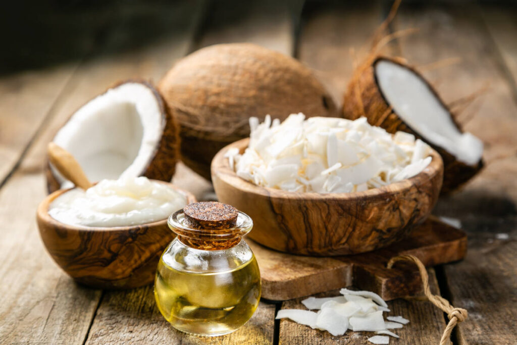 Indian superfood coconut whole fruit, flakes and oil on wooden table.