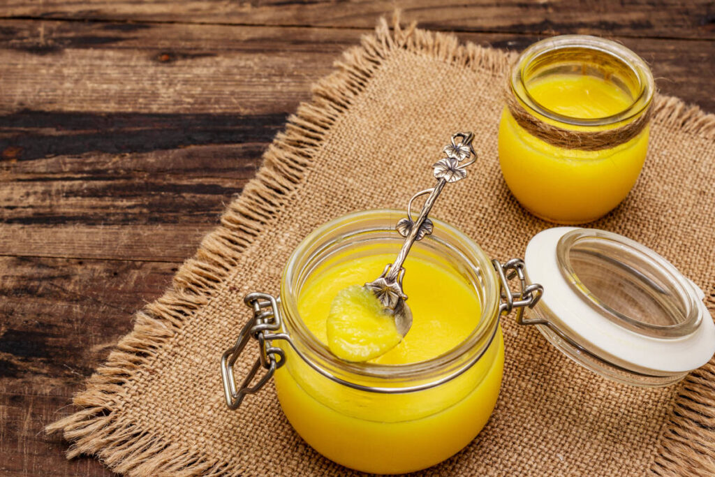 Indian superfood ghee in glass jaw on wooden table with spoon