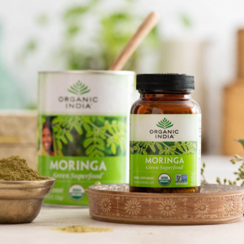 Moringa supplement in capsules and powder on a table and wooden stand.