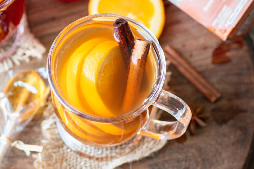 Golden Tulsi Turmeric Chai Mulled Tea with cinnamon and orange in clear tea mug.  