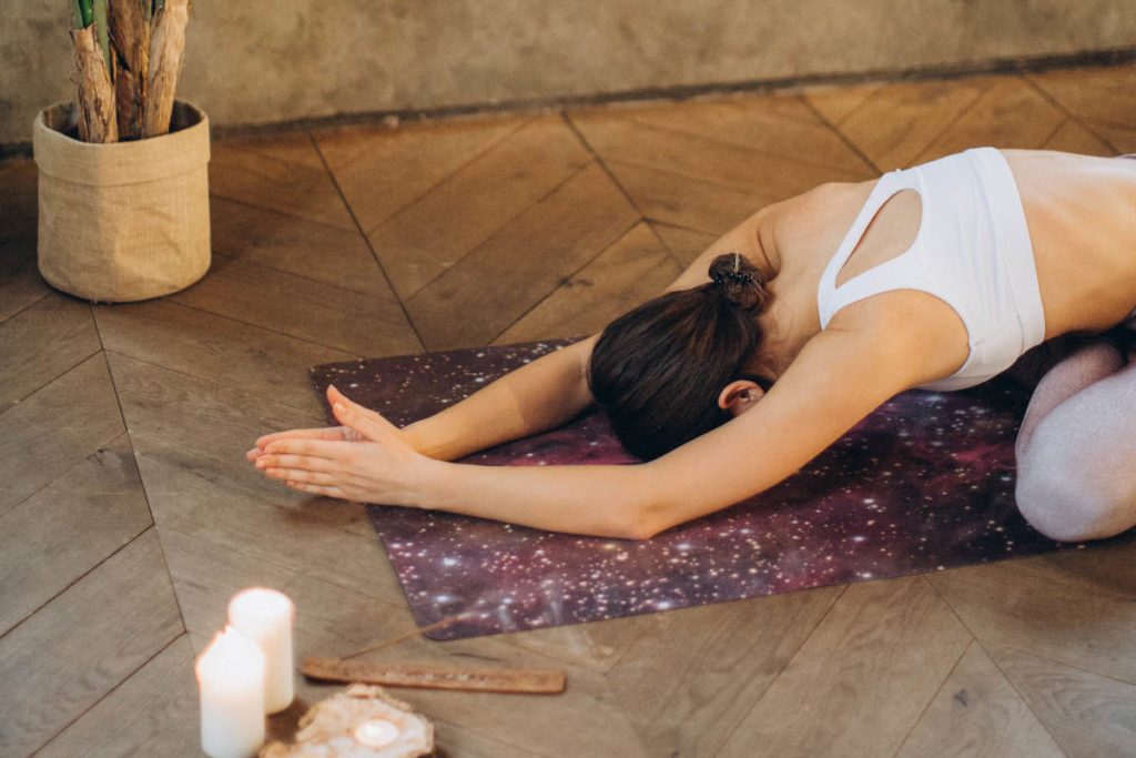 women practicing meditation on space-inspired yoga mat to nurture her intentions for the new year.