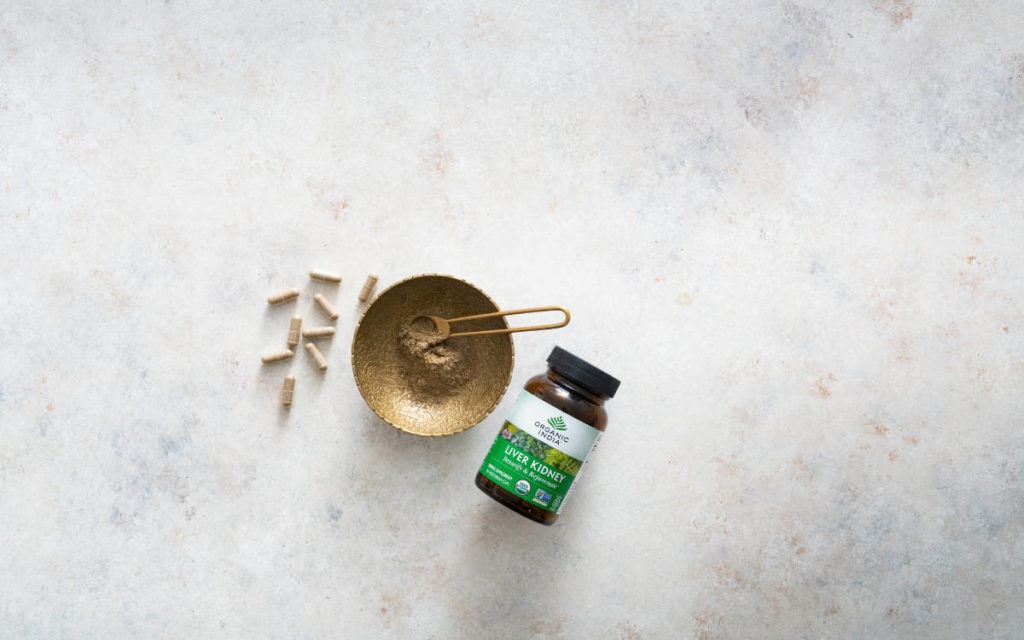 Liver Kidney powder and capsules on a marble counter with gold bowls, one of the 7 Organic India favorites.