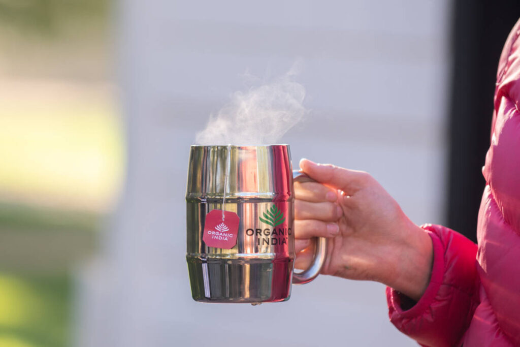 Tulsi tea in a metal mug with steam rising. 