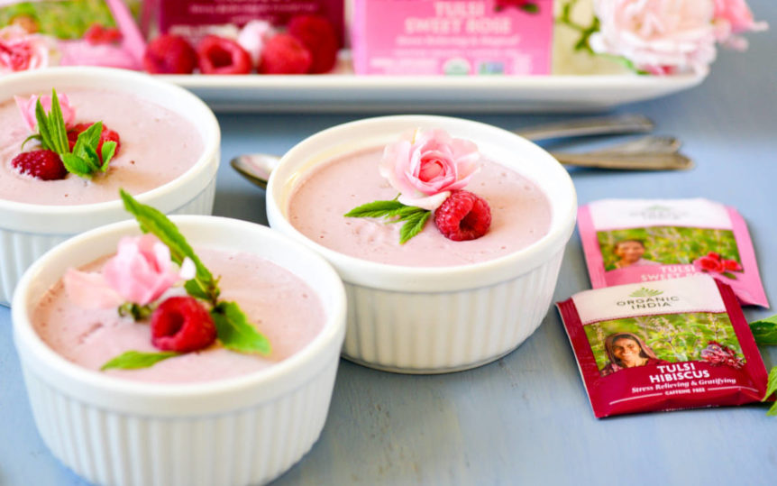 # individual dessert cups filled with pink berry mousse and garnished with rose and raspberry.