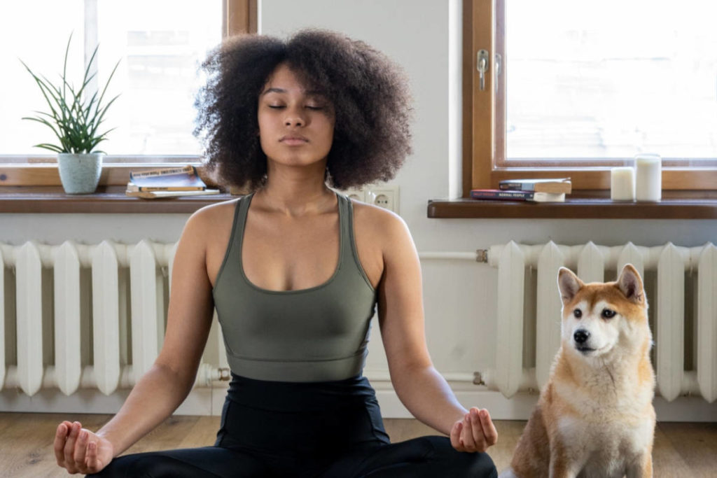 Woman in her home with her dog in a meditative pose practicing pranayama.