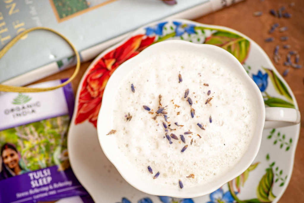 Creamy sleep tea latte in a teacup with fresh lavender garnish.