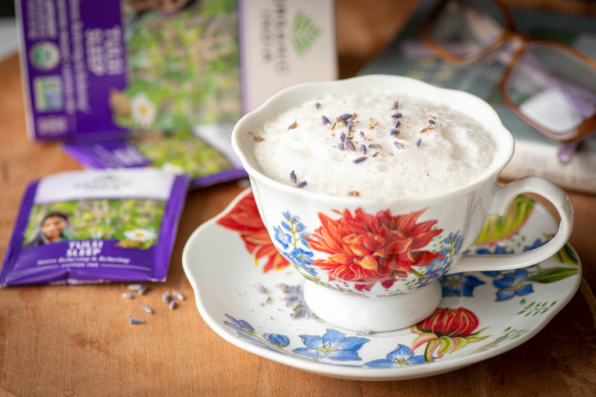 Sleep tea latte in a floral teacup on wooden table with tea bag.