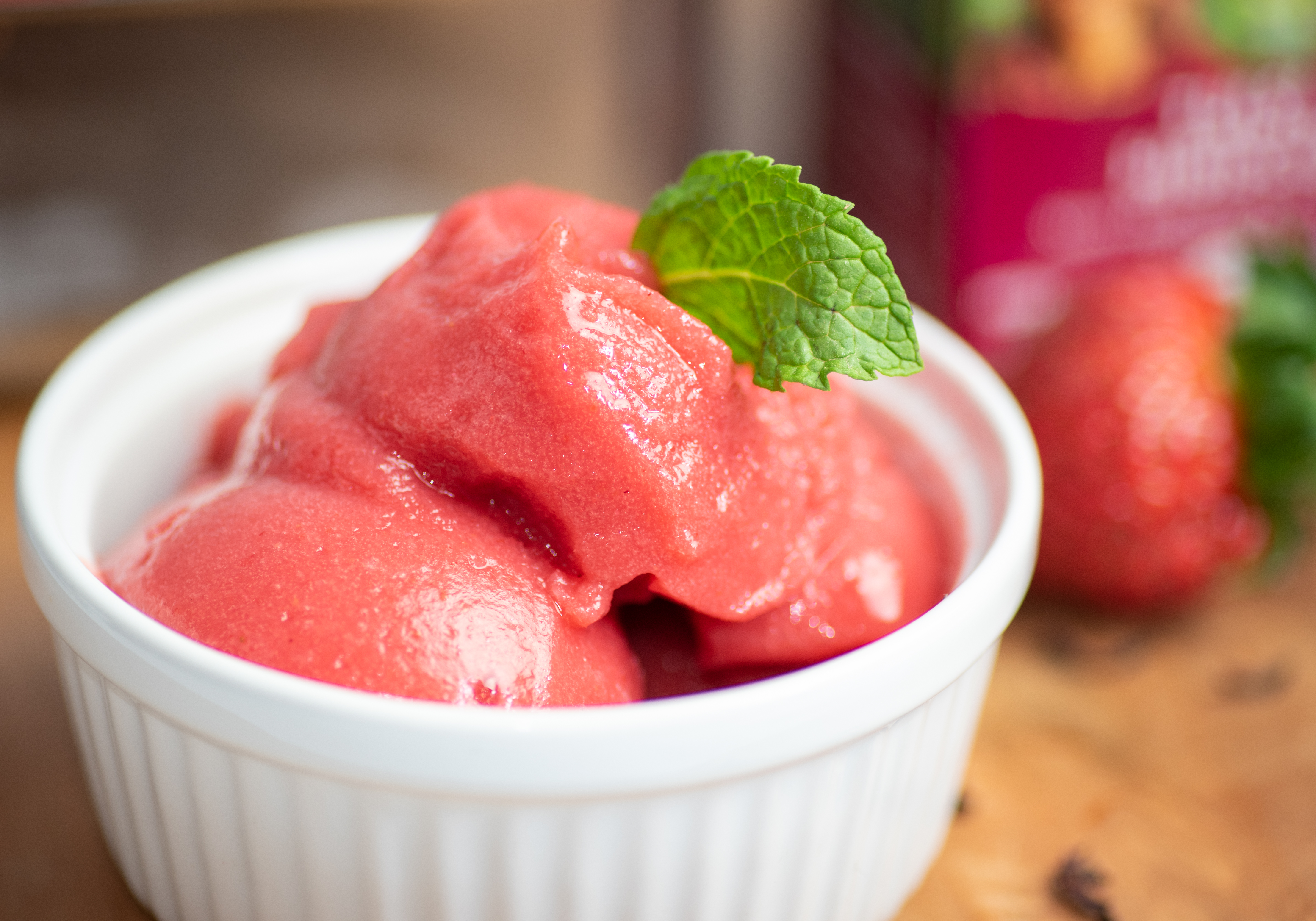 Tulsi Hibiscus sorbet in a white desert cup with a fresh mint leaf. 