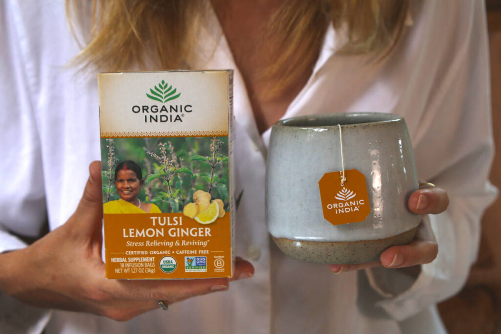 Woman holding a handmade mug of tulsi lemon ginger tea for stress and digestion