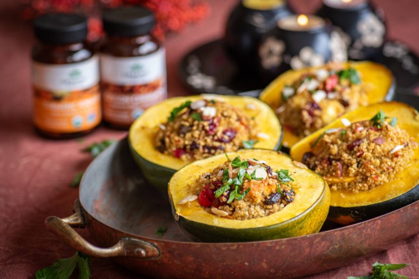 Stuffed acorn squash with a spiced quinoa cranberry stuffing in a copper serving dish