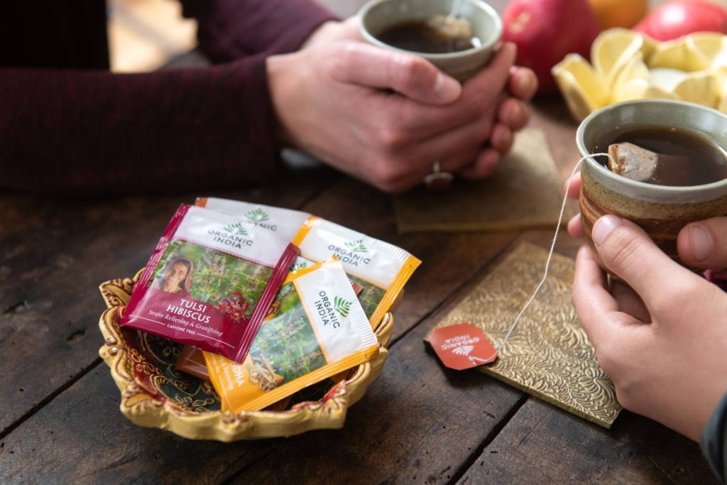 Two people hold a cup of tea in their palms with fruit for pleasant tea pairings 