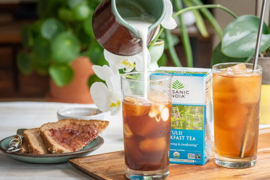 Tulsi iced breakfast tea in clear glass with tea ice cubes and toast.