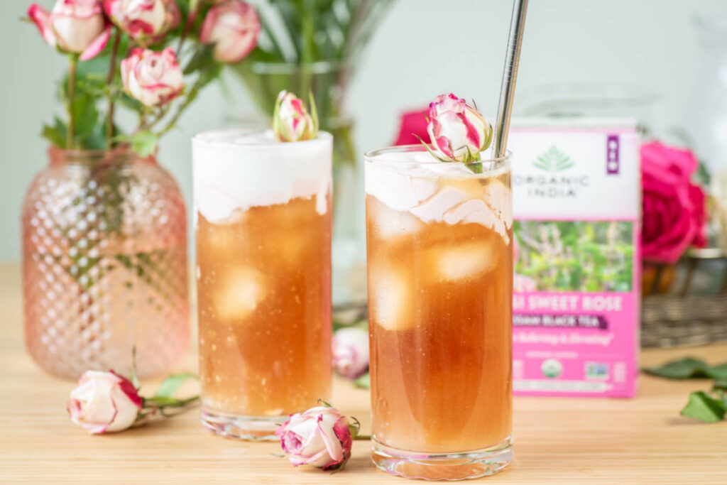 Tulsi sweet rose cold foam tea latte in clear glass over ice with rose garnish.