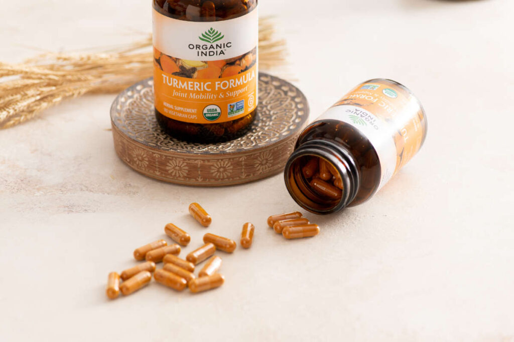 Turmeric formula supplement for runners on decorative wooden coaster on a white table. 