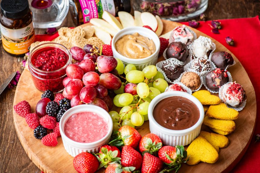 Valentine grazing board with chocolate and pink white chocolate sauce, fruits and cookies.