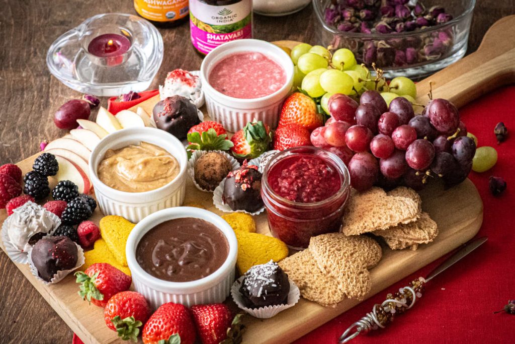 Valentine grazing board with chocolate and pink white chocolate sauce, fruits and cookies.