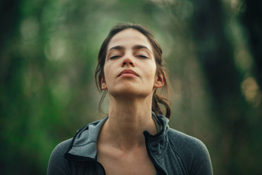 Woman in nature practicing conscious breathing.